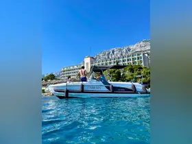 A group of people enjoys a sunny day on a boat near a stunning hotel backdrop and mountainous scenery, perfect for summer adventures on the water.