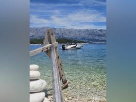 A sleek speedboat is anchored in clear waters, framed by a picturesque backdrop of mountains — a perfect scene for boating enthusiasts.