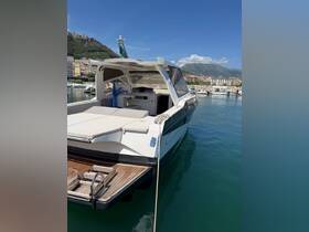 A sleek yacht docked in a serene marina, showcasing its elegant design against a backdrop of mountains and clear blue skies.