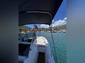 A clear view of a speedboat docked with a scenic backdrop of mountains and buildings, showcasing its sleek design and inviting atmosphere for boating adventures.