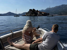 A couple enjoys a scenic boat ride with stunning views of an island in the background, perfect for romantic getaways or relaxing adventures on the water.