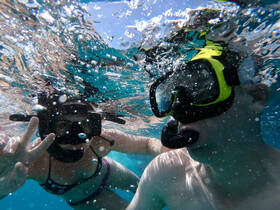 A couple enjoys snorkeling underwater, capturing the vibrant marine life and the joy of their aquatic adventure.