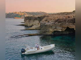 A couple enjoys a serene moment aboard a boat near stunning coastal cliffs, capturing the essence of a perfect getaway on the water.