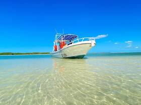 A scenic view of a boat anchored in shallow waters, showcasing its sleek design against a vibrant blue sky — perfect for exploring coastal destinations.