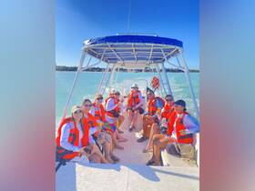 A lively group of friends enjoys a fun day on the water, celebrating with drinks aboard a boat, perfect for memorable outings and adventures.