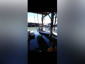 A small boat is suspended at a dock, showcasing its sleek design against the tranquil waters — perfect for fishing or leisure outings.