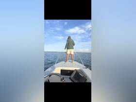 A man stands at the bow of a boat, casting a fishing line into the water, showcasing the thrill of fishing adventures on the open sea.