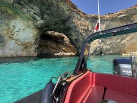 A stunning view from a boat approaching a natural cave, surrounded by crystal-clear turquoise waters — a perfect spot for exploring coastal wonders.