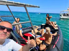 A lively group enjoys a sunny day on a boat, sharing smiles and thumbs up — perfect for a fun day out on the water.