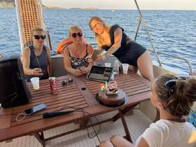 A joyful birthday celebration on a boat with friends, featuring a delicious cake and drinks, perfect for memorable moments on the water.