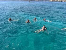 A lively group enjoys swimming in crystal-clear waters, showcasing the perfect summer day on the water.