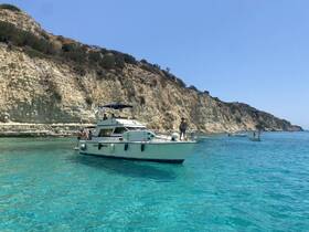 A scenic view of a boat anchored in crystal-clear waters near a stunning coastline, perfect for swimming and enjoying the summer sun.
