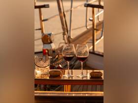 A beautifully set table featuring two glasses of red wine and a bucket of ice, perfect for enjoying a relaxing evening on the water during sunset.