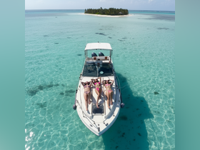 A group of friends relaxes on the deck of a boat, sunbathing under the sun with a picturesque island in the background — an ideal scene for a tropical getaway.