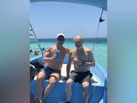 Two friends enjoy cocktails on the deck of a boat, soaking up the sun and celebrating a perfect day on the water.