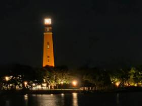 A nighttime view of a lighthouse illuminated against a dark sky, creating a serene yet unclear scene.