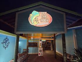 A nighttime view of the 'Off the Hook' sign at a harbor, showcasing a vibrant and inviting atmosphere for visitors.