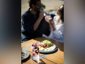 A refreshing spread of cocktails and fruit snacks is enjoyed by a couple aboard a boat, perfect for a relaxing day on the water.