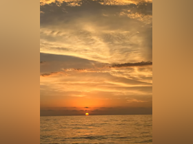 A stunning sunset over the ocean, casting golden hues across the water — a perfect backdrop for evening boat cruises.
