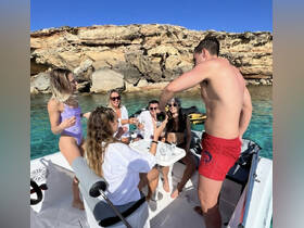 A lively group enjoys a celebration on a boat, pouring drinks and soaking up the sun — the perfect summer getaway experience.