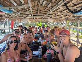 A lively group of friends enjoys a fun-filled day on the water, celebrating with drinks and laughter under a thatched roof. Perfect for bachelorette parties or group getaways!