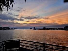 A serene sunset view over the water, featuring a sailboat in the distance — perfect for capturing the tranquility of evening boat outings.