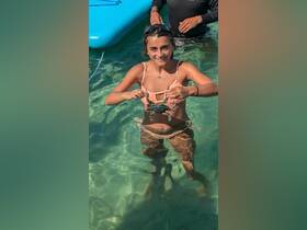 A young girl joyfully holds a crab while swimming in clear waters, showcasing a fun and interactive wildlife experience.