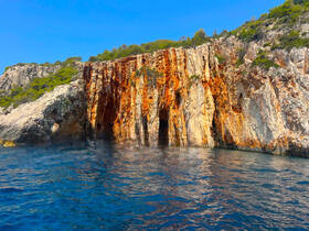 Stunning view of vibrant rock formations along the coastline, showcasing the natural beauty of the area — perfect for scenic boat tours.