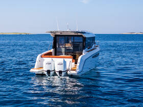 A sleek yacht is captured from the back, cruising through calm waters, showcasing its modern design and powerful twin engines.