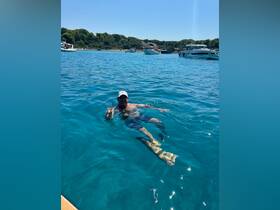 A man enjoys a refreshing drink while swimming in crystal-clear waters, capturing the essence of summer fun on the water.