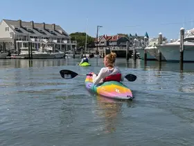 Two kayakers navigate through calm waters near a marina, enjoying a sunny day on the water — perfect for outdoor adventures and scenic exploration.
