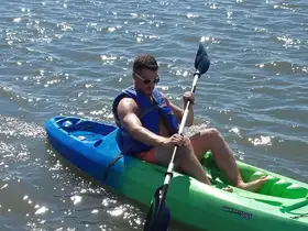 A man enjoys kayaking on sparkling waters, showcasing the thrill of on-water activities and adventure.