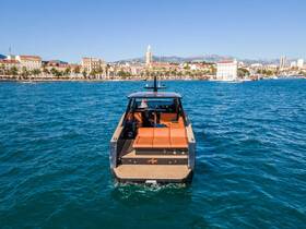A stunning view of a sleek yacht from the back, cruising through clear waters with a picturesque coastal backdrop, perfect for luxury boating experiences.