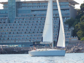 A sleek sailboat navigates the waters near a luxurious hotel, showcasing the perfect blend of relaxation and adventure on the water.