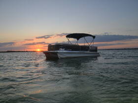 A serene sunset view of a pontoon boat docked on calm waters, perfect for evening cruises and relaxation.