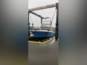 A fishing boat is being lifted at the Grand Harbour dock, showcasing the vessel's structure amidst rainy weather.