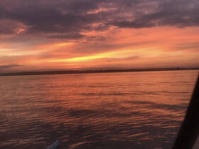 A stunning sunset reflects on calm waters, creating a picturesque scene perfect for evening boat rides.