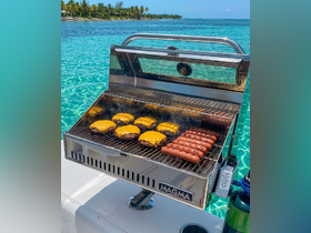 A close-up of a Magma grill on a boat, featuring sizzling hamburgers and hot dogs, perfect for a fun day on the water.