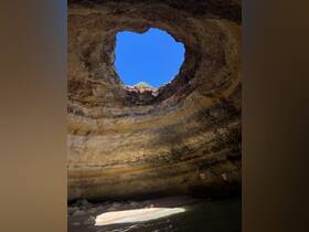 A stunning view from inside a cave, showcasing a natural skylight and the vibrant blue sky above — a picturesque landmark perfect for exploring coastal wonders.