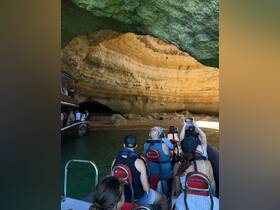 A group of guests enjoys a scenic boat tour exploring a stunning cave, capturing the moment with their cameras — a perfect adventure for nature lovers.