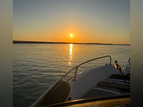 A serene sunset view from the bow of a boat, showcasing the tranquil waters and the fading light — perfect for evening cruises.