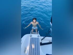 A young man enjoys a refreshing swim in crystal-clear blue waters, showcasing the perfect summer day on the boat.