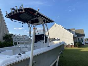A side view of a center console boat parked on a lawn, showcasing its sleek design and features against a clear blue sky.