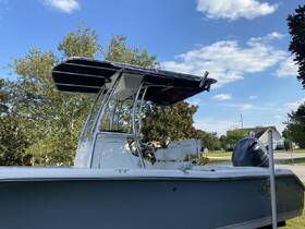 A detailed view of a center console boat docked, showcasing its sleek design and features under a clear blue sky.