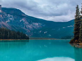 A breathtaking view of a tranquil lake surrounded by majestic mountains and lush forests, perfect for nature lovers and outdoor enthusiasts.