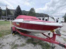 A vibrant red Four Winns boat is docked and ready for adventure, showcasing its sleek design and trailer setup in a scenic outdoor setting.