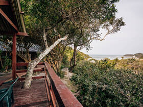 A scenic view from a wooden deck surrounded by trees, overlooking a coastal landscape. The image captures the natural beauty of the area, but lacks clarity.