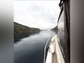 A serene view of a boat navigating through calm waters, showcasing the surrounding landscape and a distant bridge — perfect for capturing the essence of a peaceful boating experience.