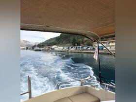 A view from the deck of a boat as it moves through calm waters, showcasing the scenic shoreline and surrounding mountains.