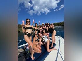 A lively group of friends celebrates with cocktails on a boat, perfect for bachelorette parties or summer gatherings on the water.